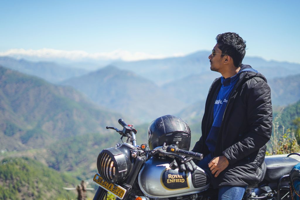 A man on a Royal Enfield enjoys a scenic mountainous view, capturing freedom and adventure.