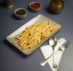 Delicious crispy French fries served with condiments on an elegant dining table setup, perfect for food enthusiasts.